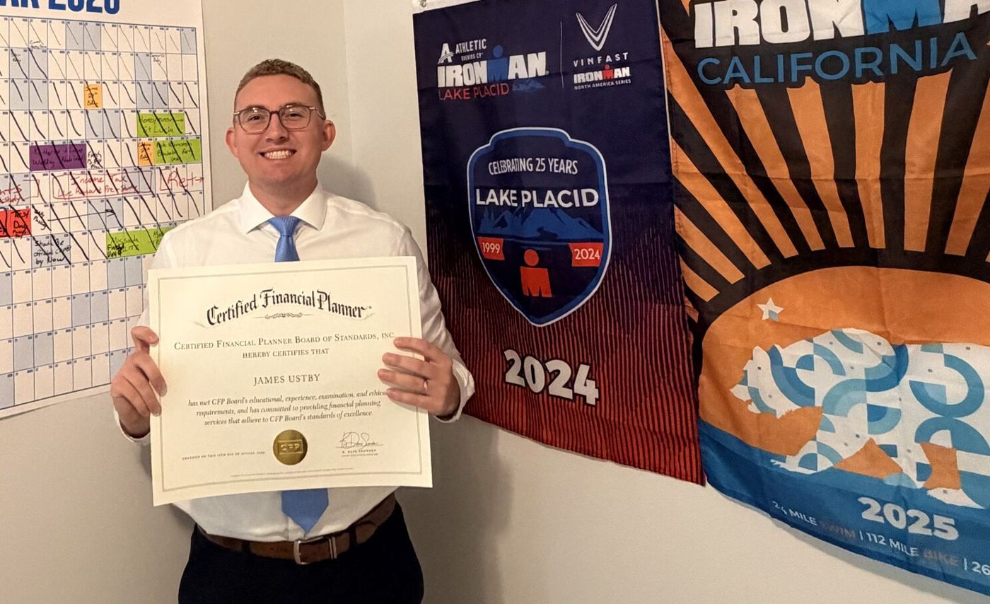 James Ustby holding his CFP® certificate in front of his Ironman Lake Placid and California flags